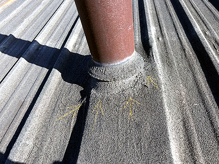 Pipe penetration in BUR Rolled Asphalt Modified Roof, has four voids at the base, with water pooled in the interior.