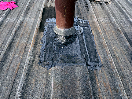 Pipe penetration in BUR Rolled Asphalt Modified Roof, has four voids at the base, with water pooled in the interior.
