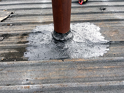 Pipe penetration in BUR Rolled Asphalt Modified Roof, has four voids at the base, with water pooled in the interior.