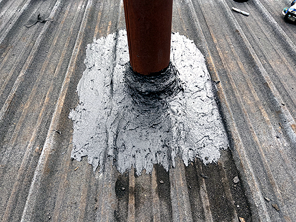 Pipe penetration in BUR Rolled Asphalt Modified Roof, has four voids at the base, with water pooled in the interior.